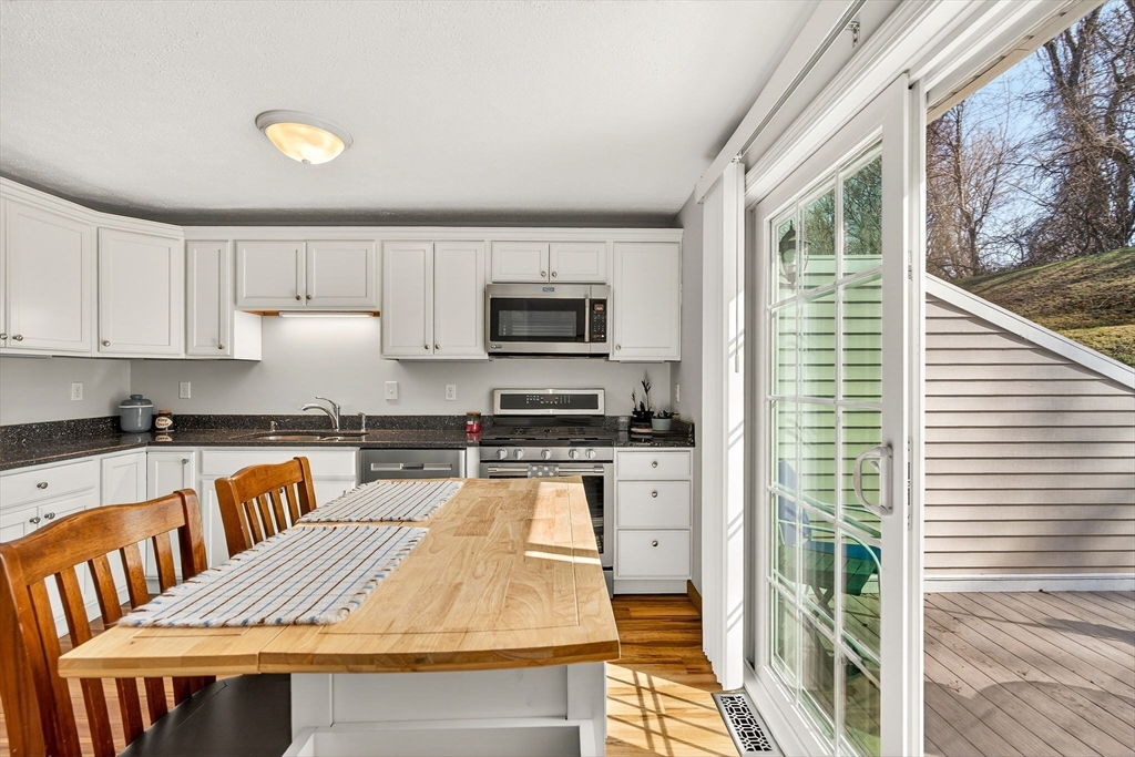 61 Fox Meadow Road, Unit A Leominster, MA 01453 - Photo 9 of 38 a kitchen with stainless steel appliances granite countertop a stove top oven a sink a dining table and chairs with wooden floor