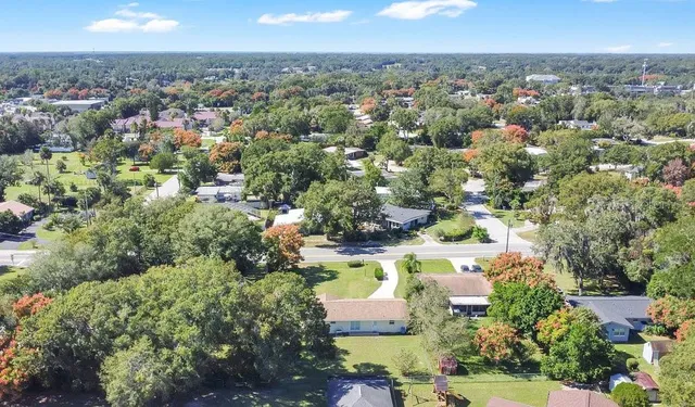 an aerial view of residential houses with outdoor space and trees