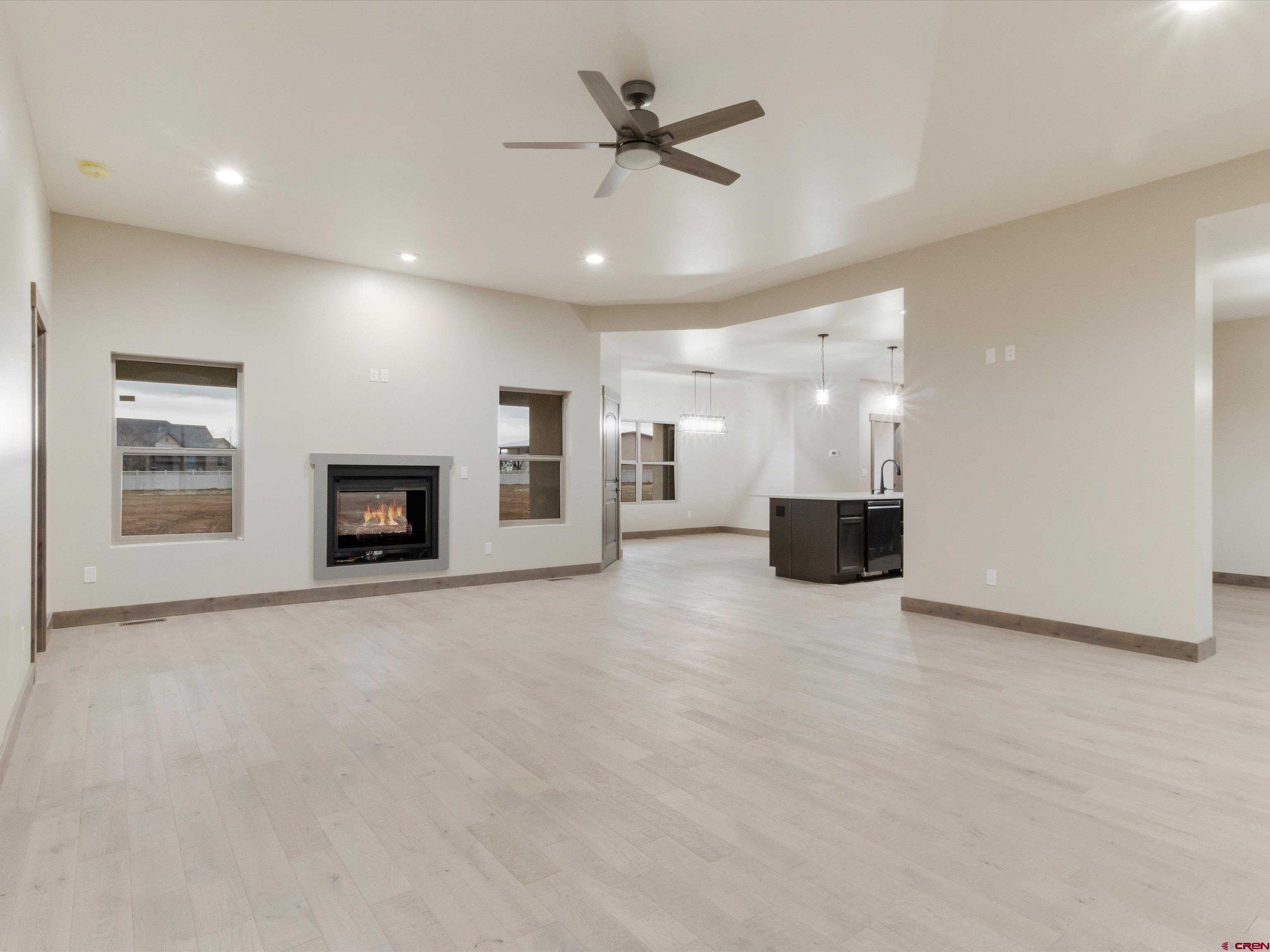 1900 Snaffle Bit Road Delta, CO 81416 - Photo 9 of 33 an empty room with a fireplace and a chandelier fan