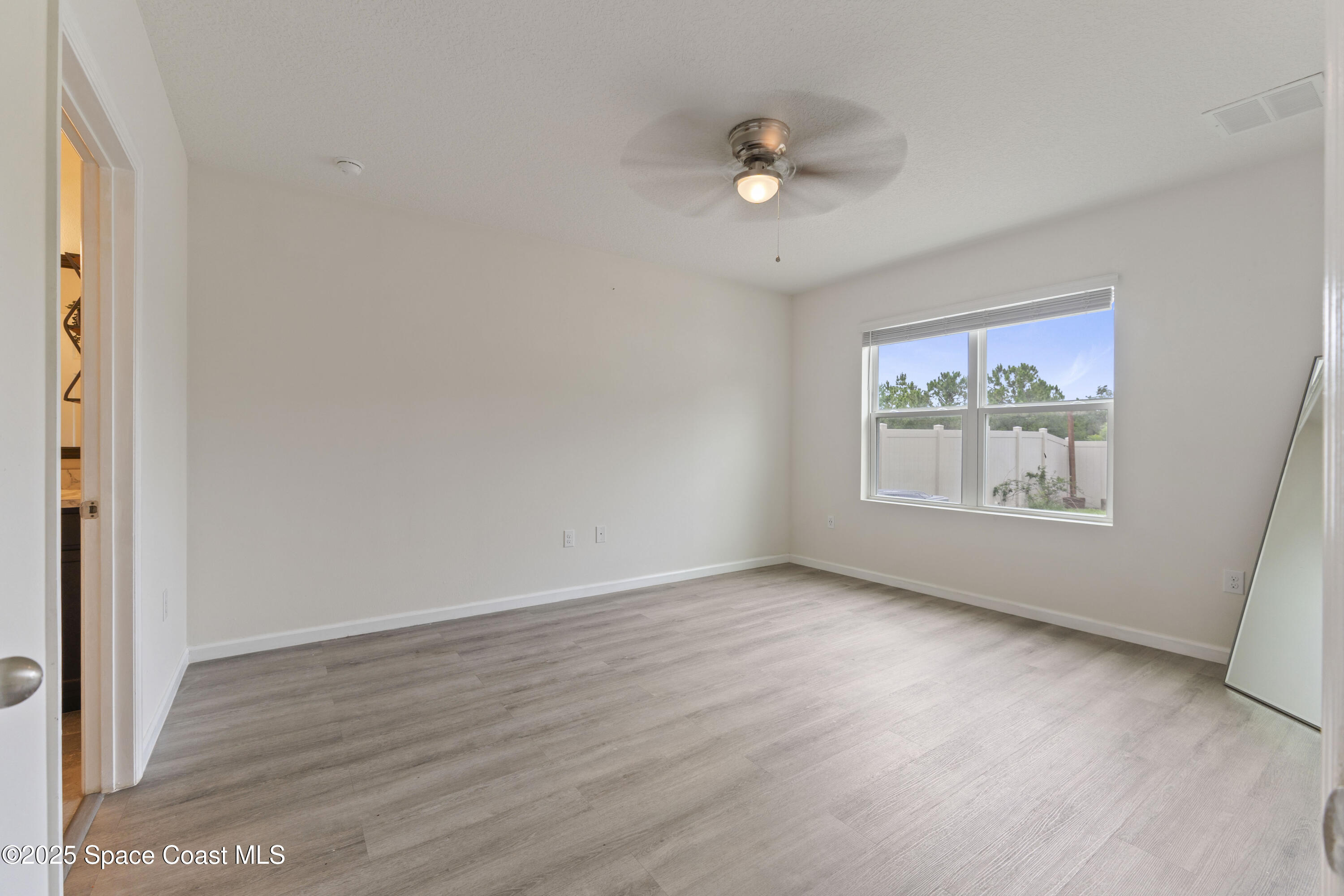 310 Forest Trace Circle Titusville, FL 32780 - Photo 14 of 36 an empty room with wooden floor fan and windows