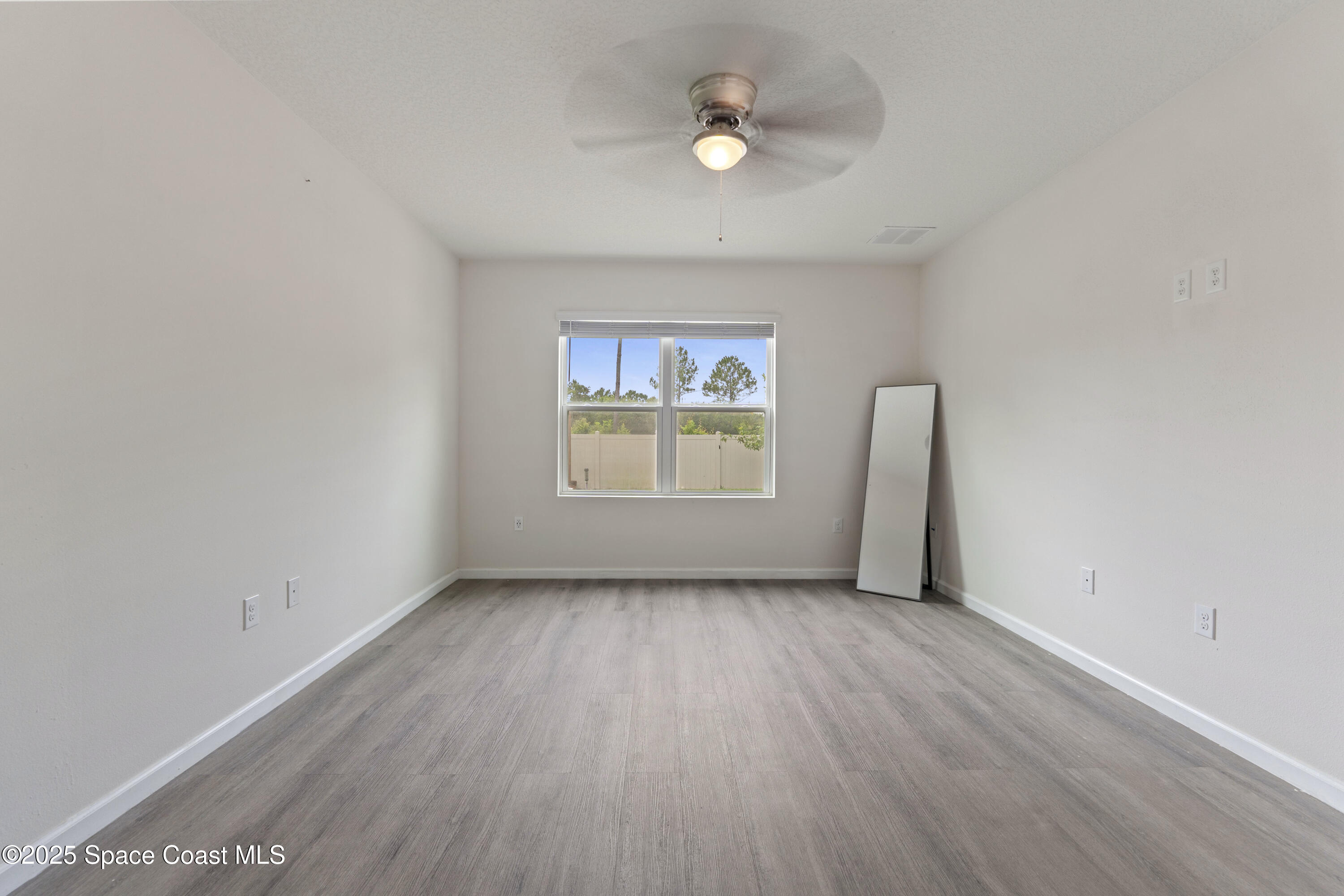 310 Forest Trace Circle Titusville, FL 32780 - Photo 15 of 36 an empty room with wooden floor chandelier fan and windows