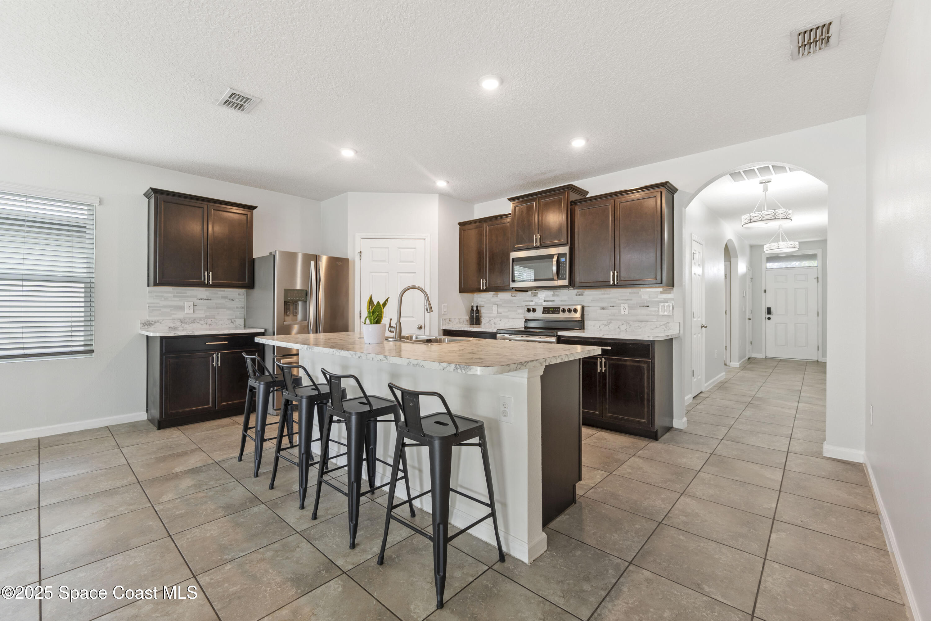 310 Forest Trace Circle Titusville, FL 32780 - Photo 5 of 36 a large kitchen with kitchen island granite countertop a stove a sink a dining table and chairs