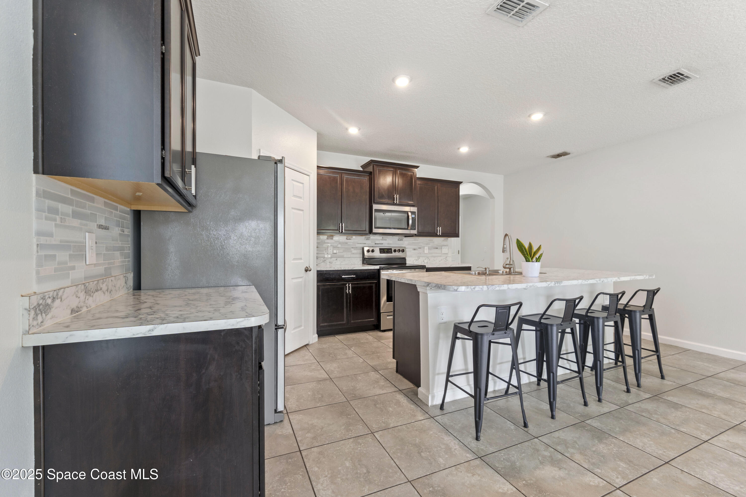 310 Forest Trace Circle Titusville, FL 32780 - Photo 7 of 36 a kitchen with kitchen island granite countertop a sink counter and chairs