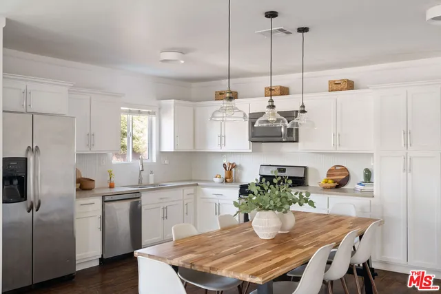 a kitchen with stainless steel appliances granite countertop a sink a microwave a refrigerator a stove and white cabinets