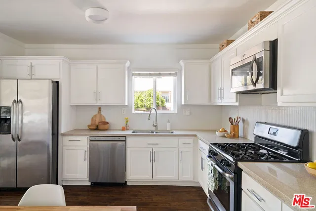 a kitchen with stainless steel appliances granite countertop a sink stove refrigerator and cabinets