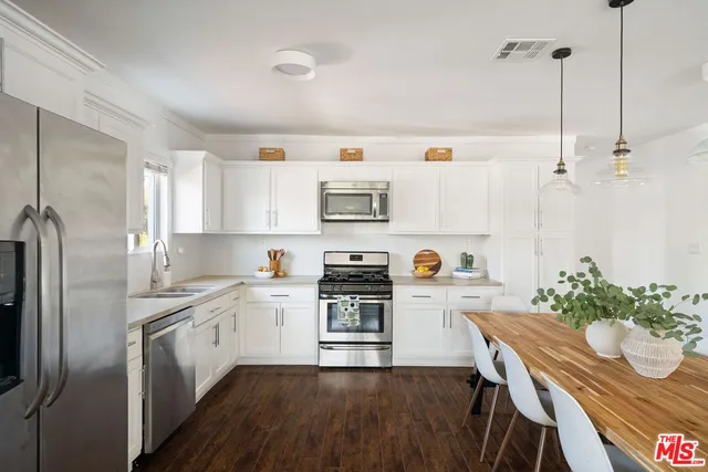 a kitchen with stainless steel appliances a stove a sink a microwave a refrigerator and white cabinets