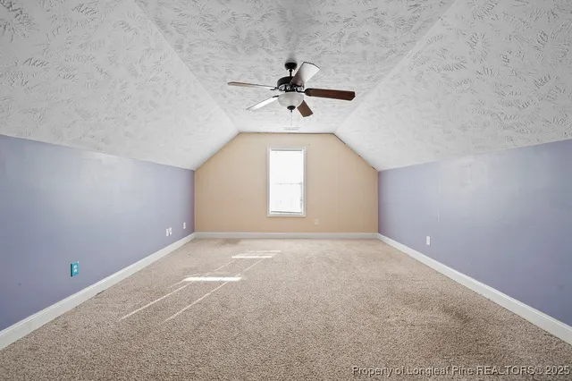 an empty room with a chandelier fan and windows