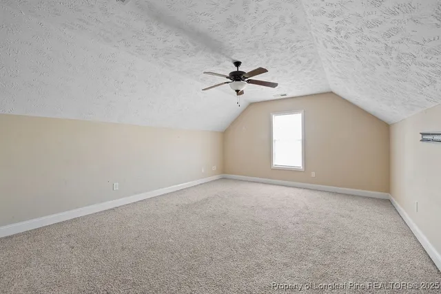 an empty room with a chandelier fan and windows