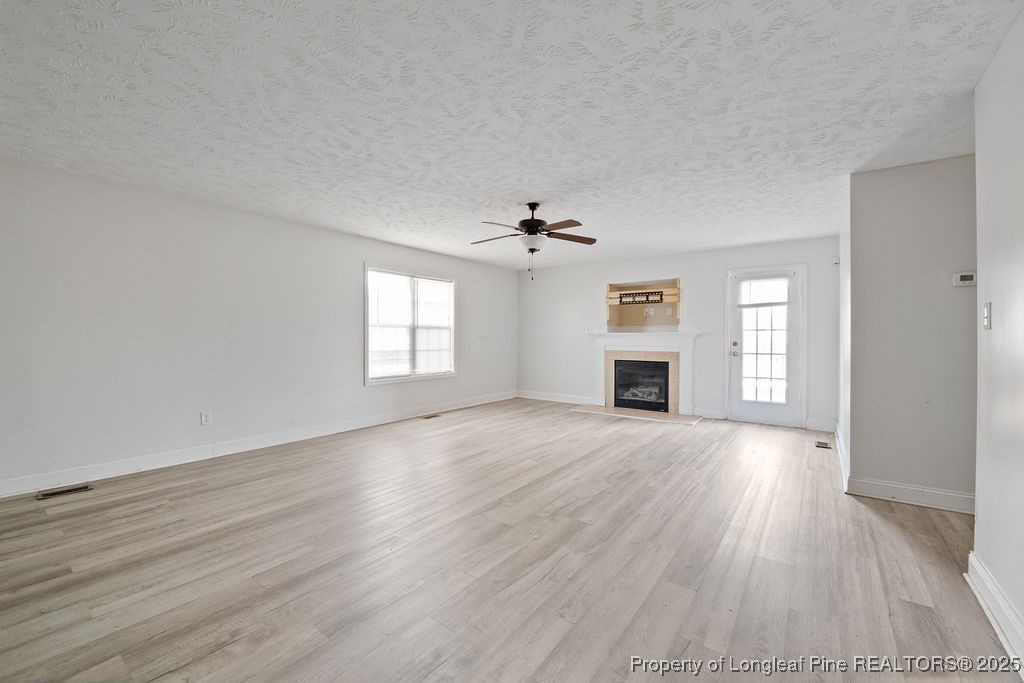 185 Sunflower Street Raeford, NC 28376 - Photo 5 of 30 an empty room with wooden floor fireplace and windows