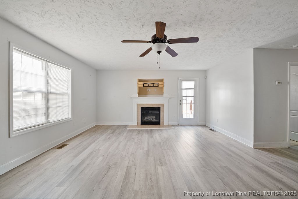 185 Sunflower Street Raeford, NC 28376 - Photo 6 of 30 an empty room with windows fireplace and wooden floor