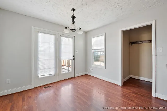 a view of an empty room with a window and wooden floor
