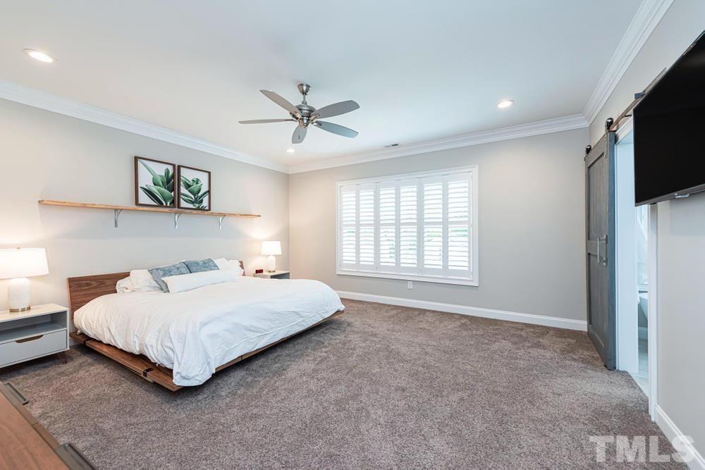 714 Edmund Street Raleigh, NC 27604 - Photo 14 of 30 Primary Bedroom on upper level with large window, crown molding, and ceiling fan.