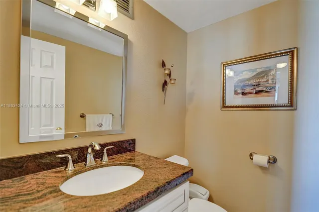 a bathroom with a granite countertop sink mirror vanity and toilet