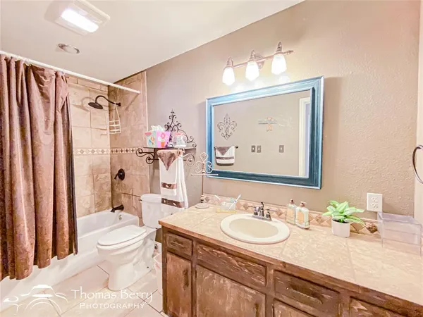 a bathroom with a granite countertop sink a toilet a mirror a vanity and shower