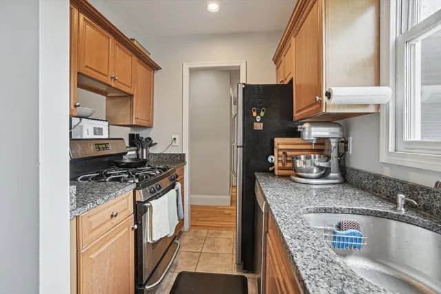 a kitchen with granite countertop stainless steel appliances a sink stove and a window