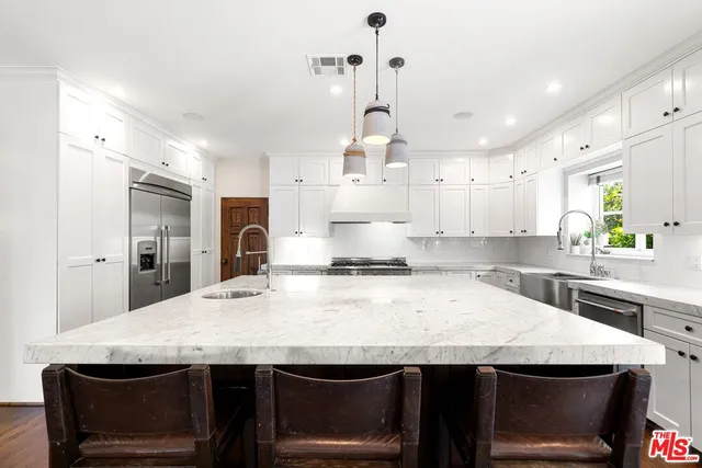 a large kitchen with a counter space a sink appliances and living room view