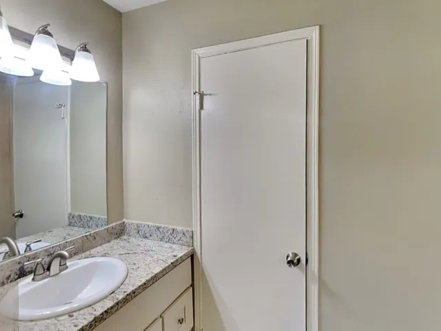 a bathroom with a granite countertop sink and a mirror