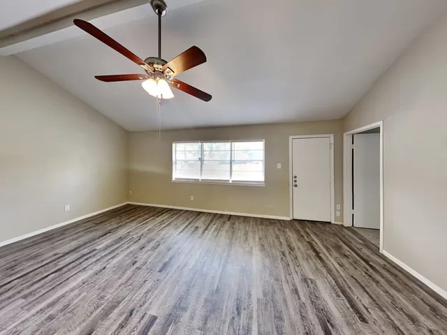 a view of an empty room with wooden floor and a window