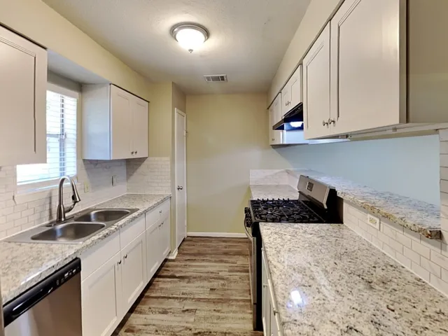 a kitchen with granite countertop a sink and cabinets