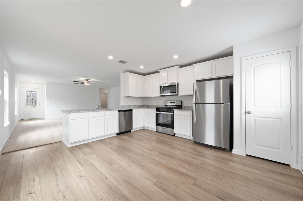 585 Aplite Pass Maxwell, TX 78656 - Photo 5 of 13 a kitchen with white cabinets and stainless steel appliances