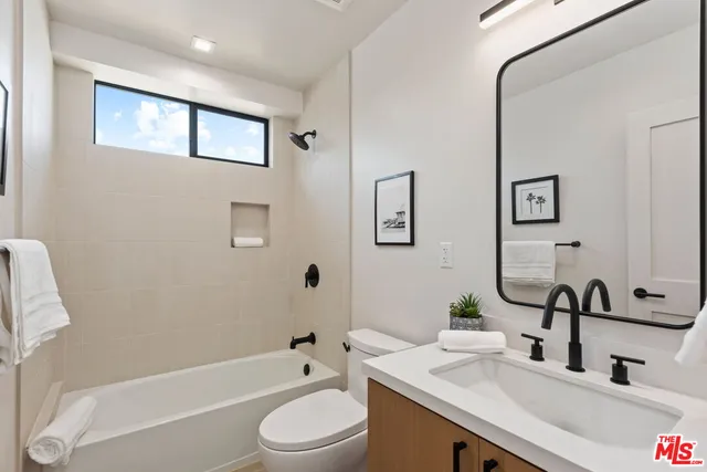 a bathroom with a granite countertop sink a toilet a mirror a bathtub and shower