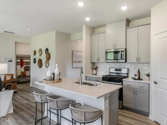 a kitchen with stainless steel appliances a sink a stove a refrigerator cabinets and a dining table