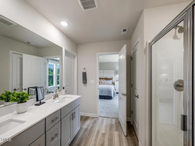 a en suite bathroom with a double vanity sink a mirror and shower