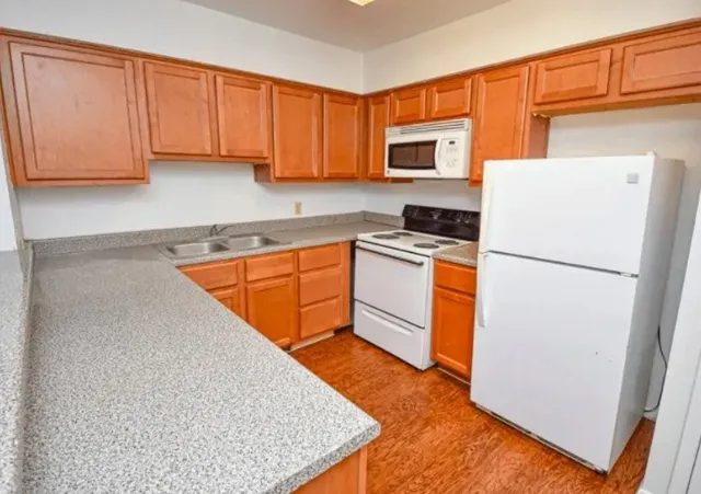 a kitchen with granite countertop a refrigerator stove top oven and cabinets