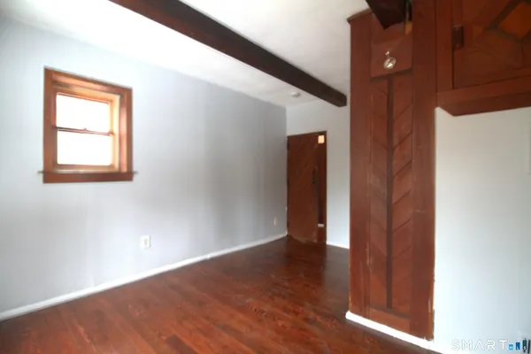 a view of an empty room with wooden floor and a fireplace