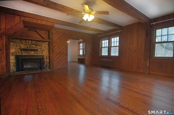 an empty room with wooden floor fireplace and windows