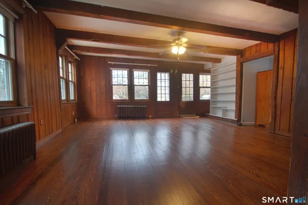 a view of empty room with wooden floor and fan