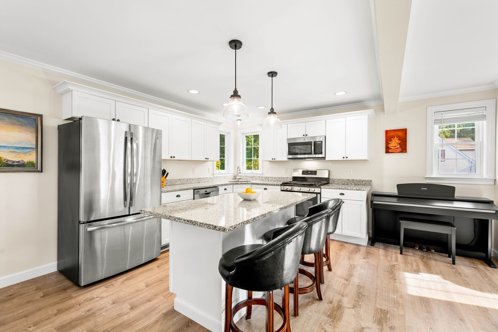 84 Ferry Road Salisbury, MA 01952 - Photo 4 of 42 a kitchen with granite countertop a refrigerator a stove a sink dishwasher a dining table and chairs with wooden floor