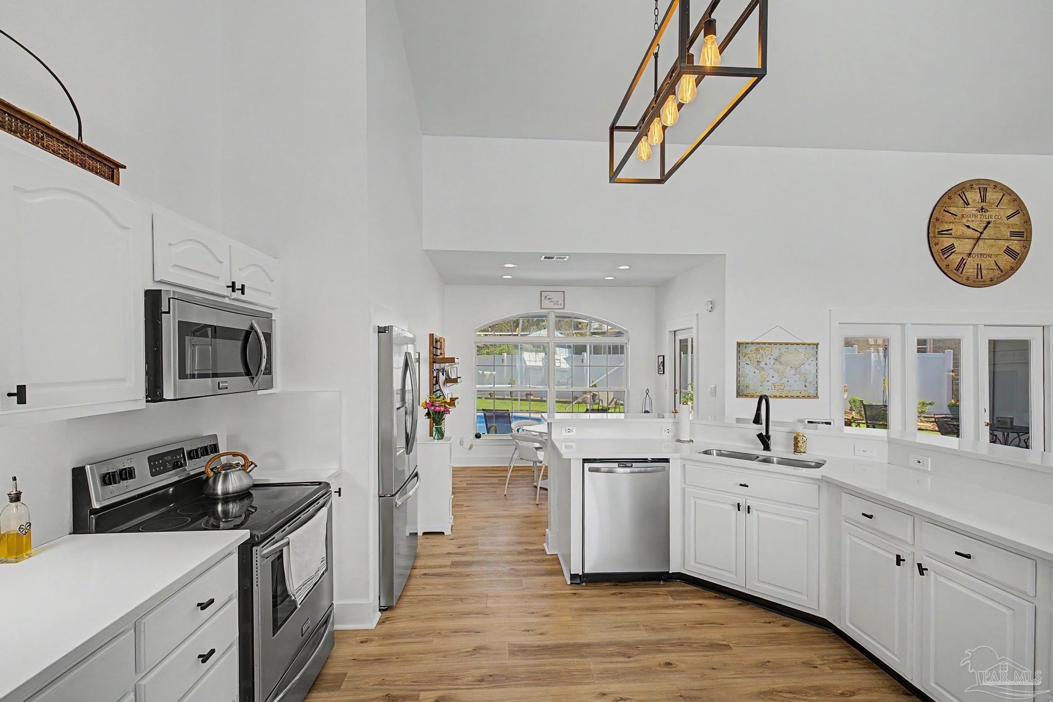 2005 Riviera Lane South Navarre, FL 32566 - Photo 14 of 70 a kitchen with stainless steel appliances granite countertop a stove top oven a sink dishwasher and white cabinets with wooden floor