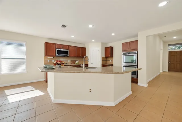 a living room with stainless steel appliances kitchen island granite countertop a refrigerator and a stove top oven