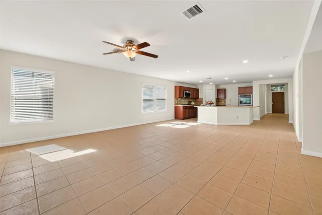 an empty room with windows and chandelier fan