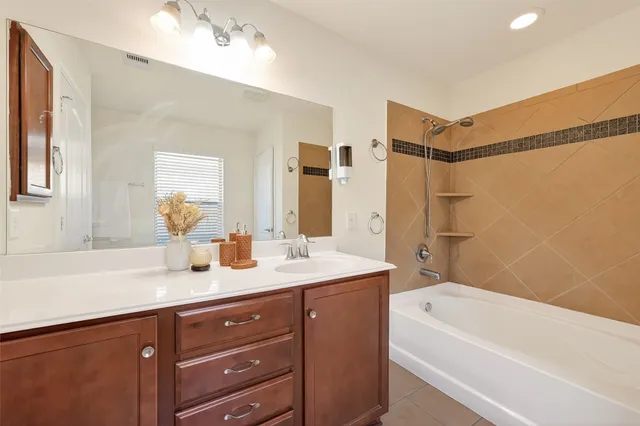 a bathroom with a granite countertop sink mirror and a bath tub