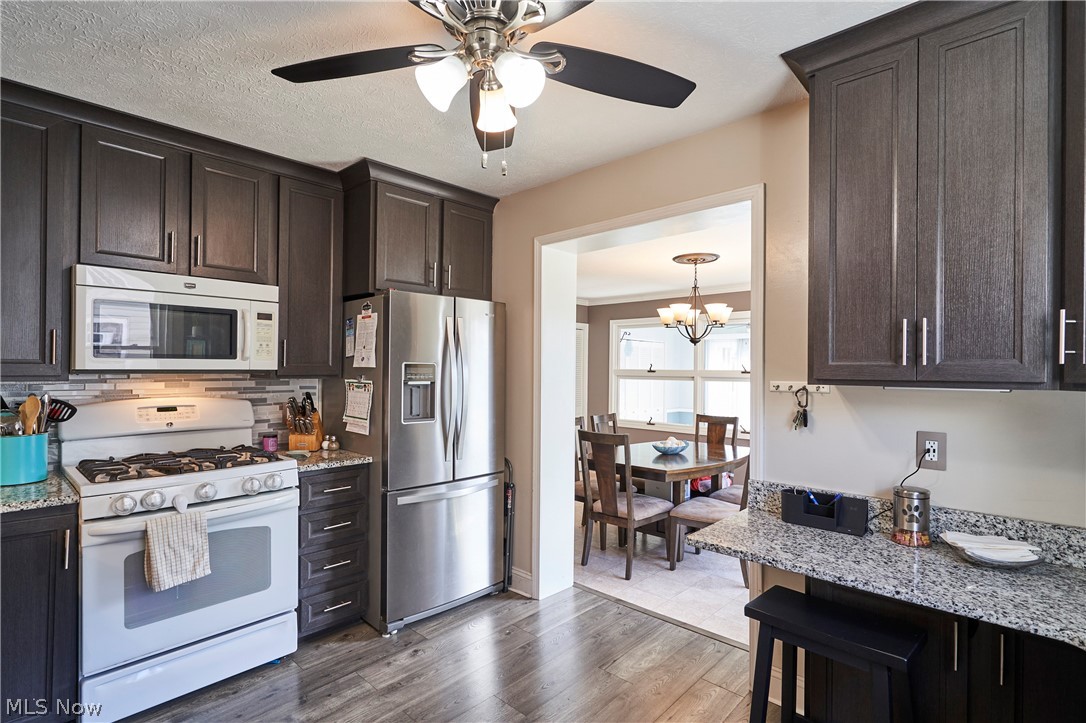 28322 Forest Road Willowick, OH 44095 - Photo 11 of 32 Kitchen with ceiling fan with notable chandelier, backsplash, white appliances, and light stone counters