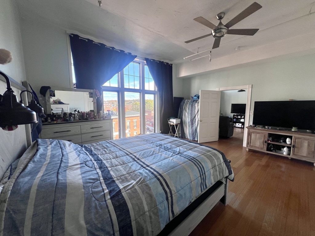 16 Merrimack Street, Unit 4A Lowell, MA 01852 - Photo 12 of 24 a bed room with a bed a television and a large window