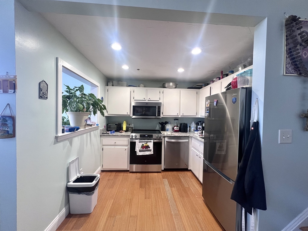 16 Merrimack Street, Unit 4A Lowell, MA 01852 - Photo 5 of 24 a kitchen with granite countertop stainless steel appliances and wooden cabinets