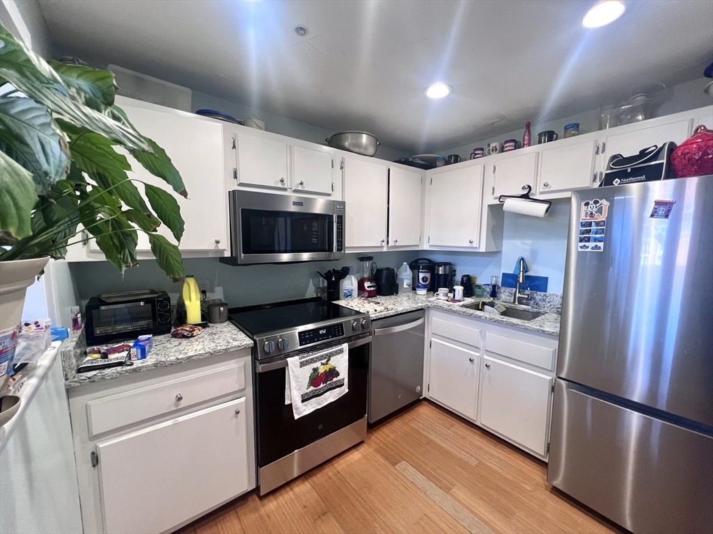 16 Merrimack Street, Unit 4A Lowell, MA 01852 - Photo 6 of 24 a kitchen with a sink stainless steel appliances and white cabinets