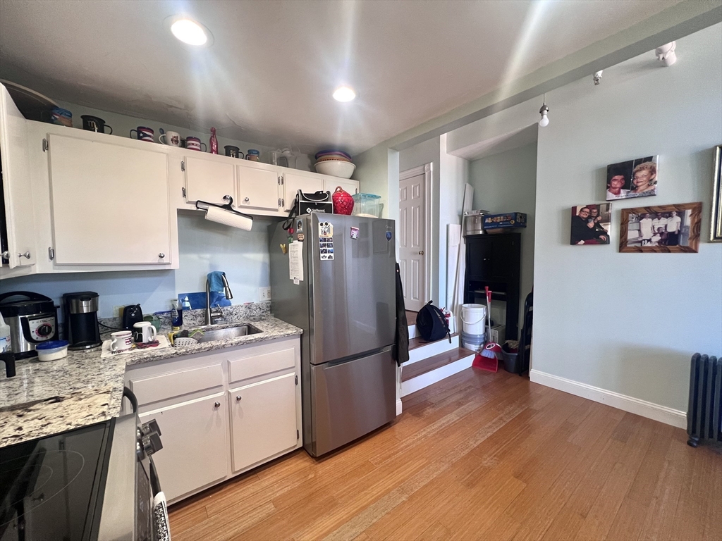 16 Merrimack Street, Unit 4A Lowell, MA 01852 - Photo 7 of 24 a kitchen with refrigerator cabinets and wooden floor