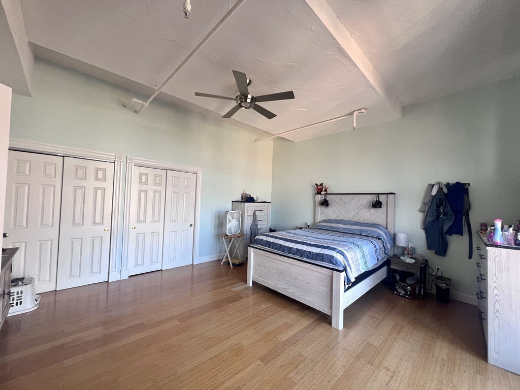16 Merrimack Street, Unit 4A Lowell, MA 01852 - Photo 8 of 24 a spacious bedroom with a bed and a chandelier