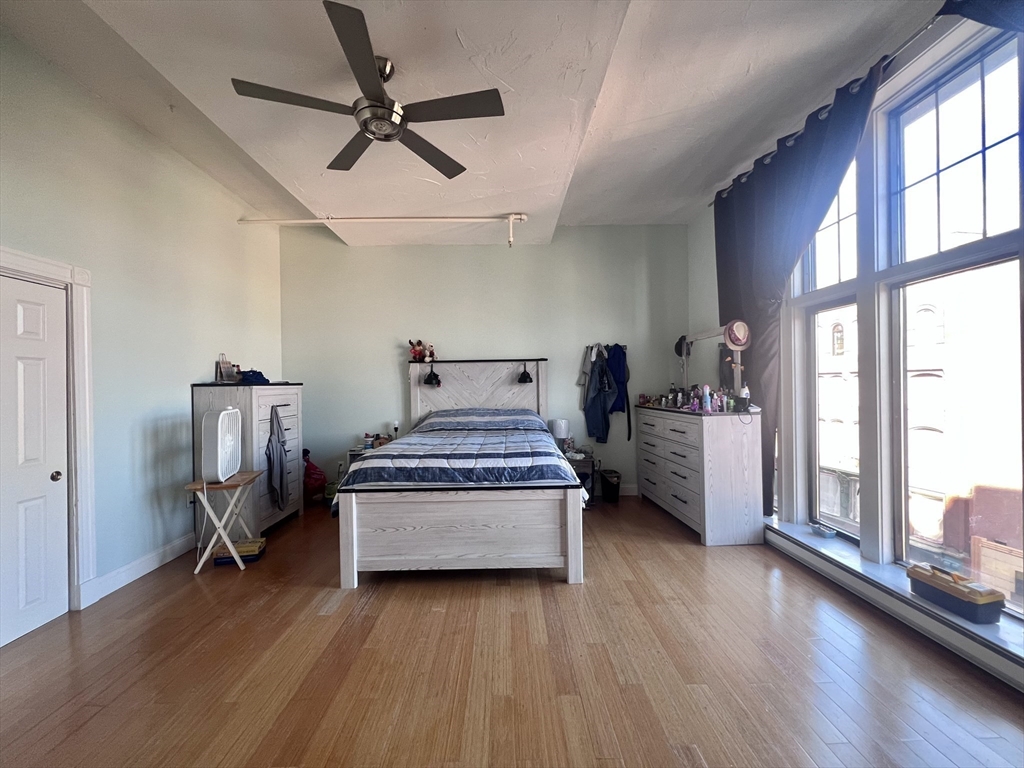 16 Merrimack Street, Unit 4A Lowell, MA 01852 - Photo 9 of 24 a bedroom with furniture window and wooden floor