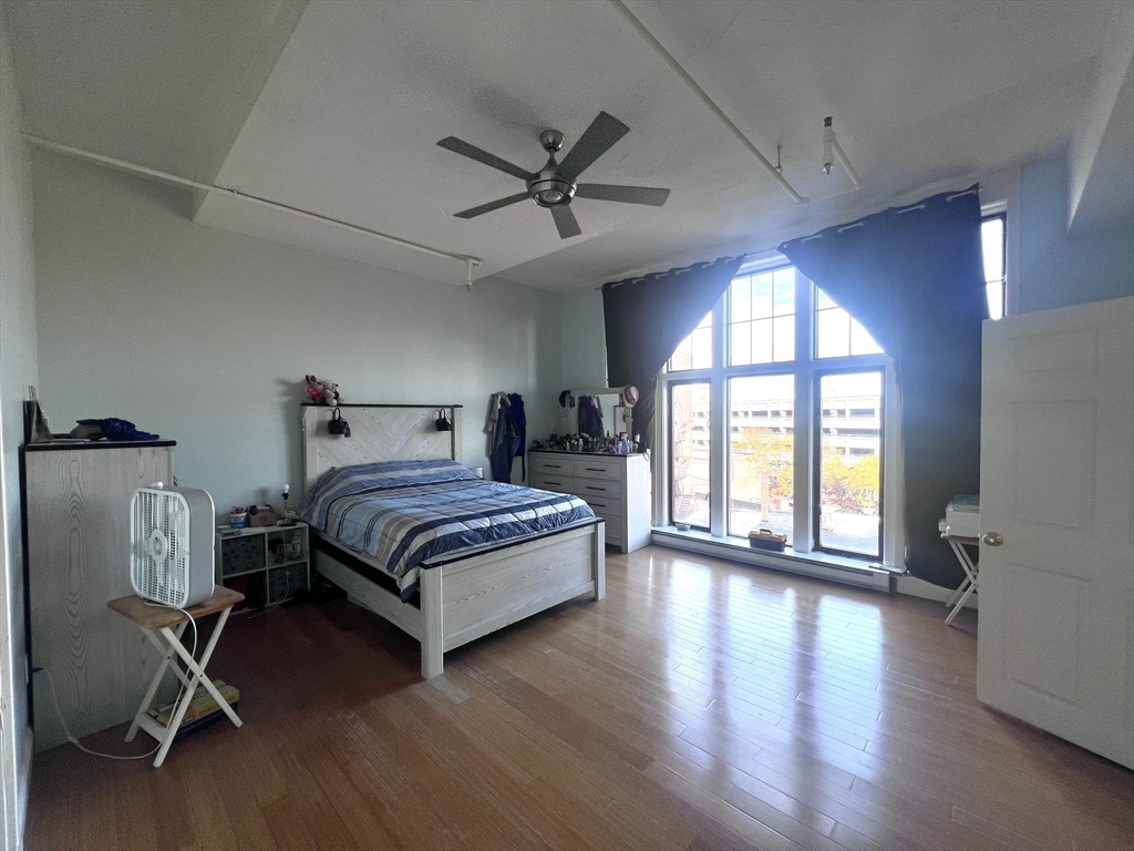 16 Merrimack Street, Unit 4A Lowell, MA 01852 - Photo 10 of 24 a bedroom with a bed mirror and a large window