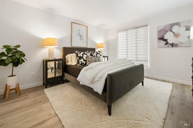 a bedroom with a bed and a potted plant on the dresser