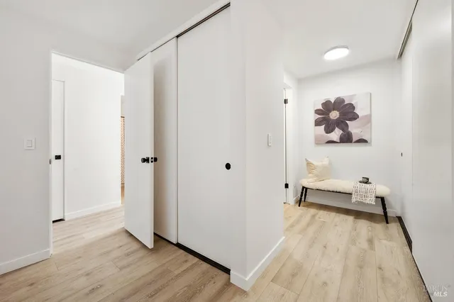 a view of a hallway with wooden floor and a bathroom