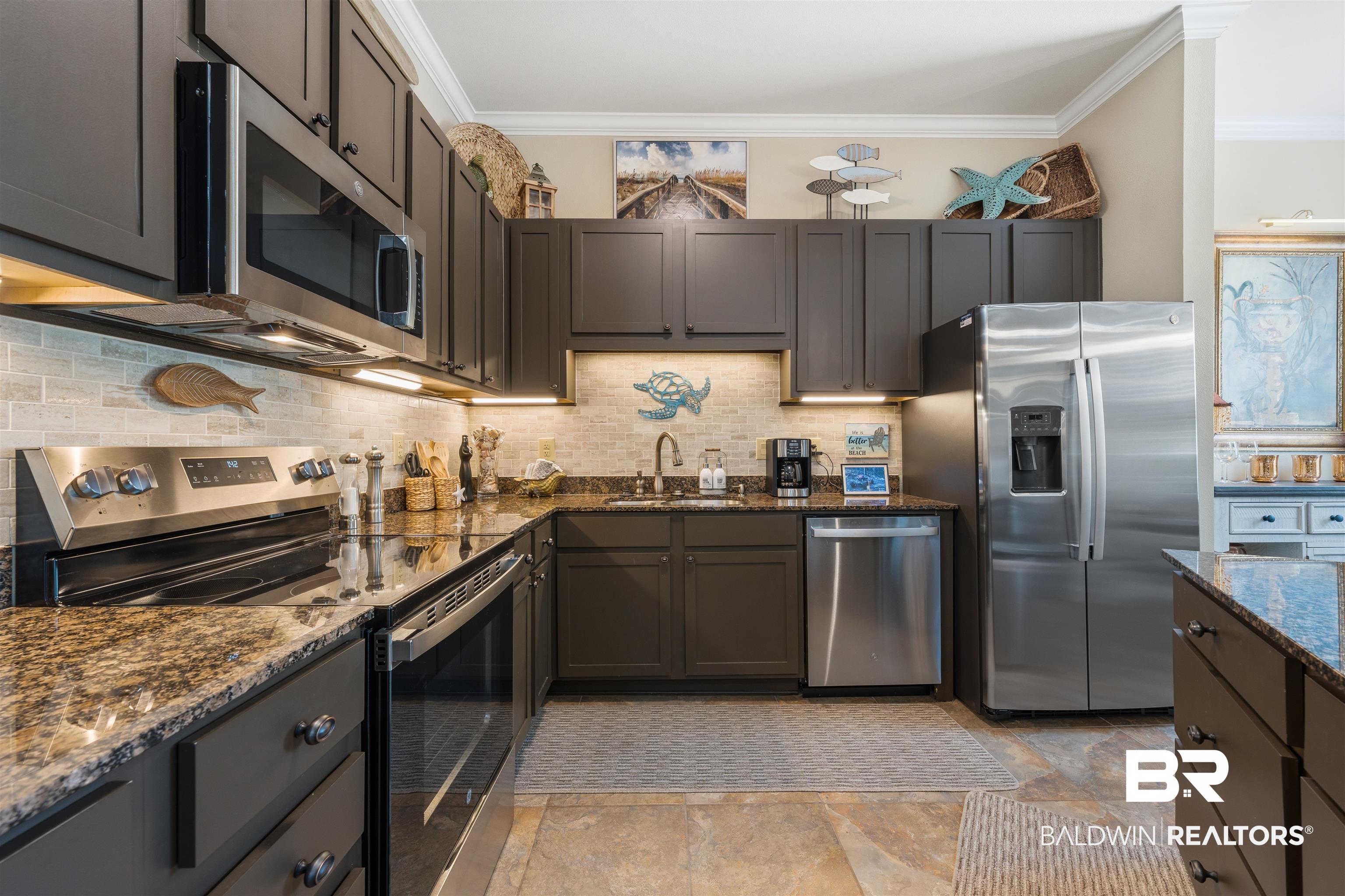 1430 Regency Road, Unit H202 Gulf Shores, AL 36542 - Photo 16 of 25 Kitchen with stainless steel appliances, dark stone counters, ornamental molding, backsplash, and dark wood finish cabinets
