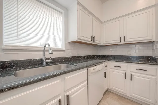a kitchen with granite countertop white cabinets and a sink