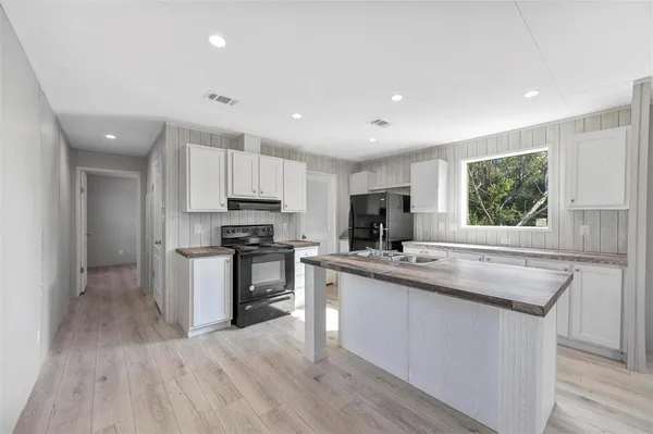 a kitchen with stainless steel appliances granite countertop a refrigerator a sink dishwasher a stove and white countertops with wooden floor