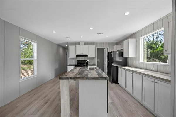 a kitchen with kitchen island granite countertop a sink wooden floor and stainless steel appliances